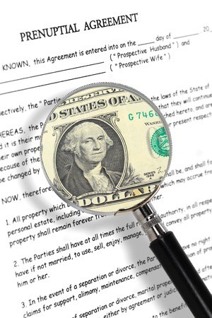 Prenuptial agreement with US dollar bill under magnifying glass.